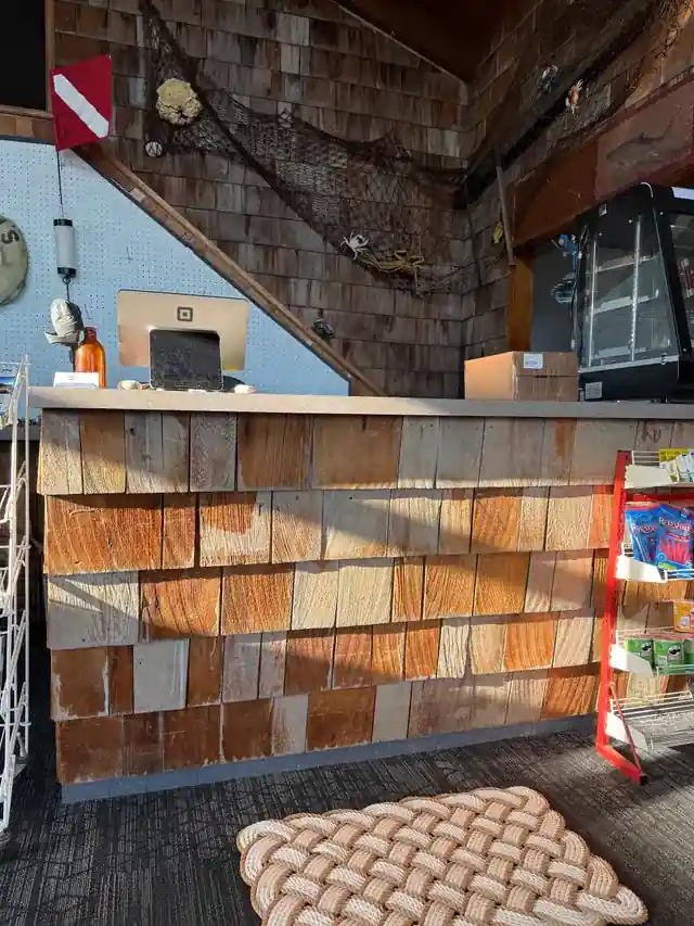 The office counter clad in cedar shingles with a dive flag and tackle shelf