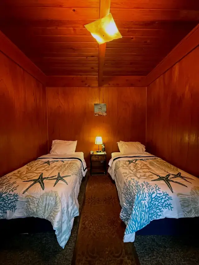 Two twin beds with starfish bedspreads in a cedar-panelled room